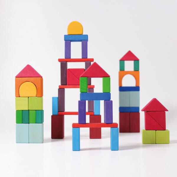 Colorful wooden building blocks arranged into a playful city skyline on a white background.