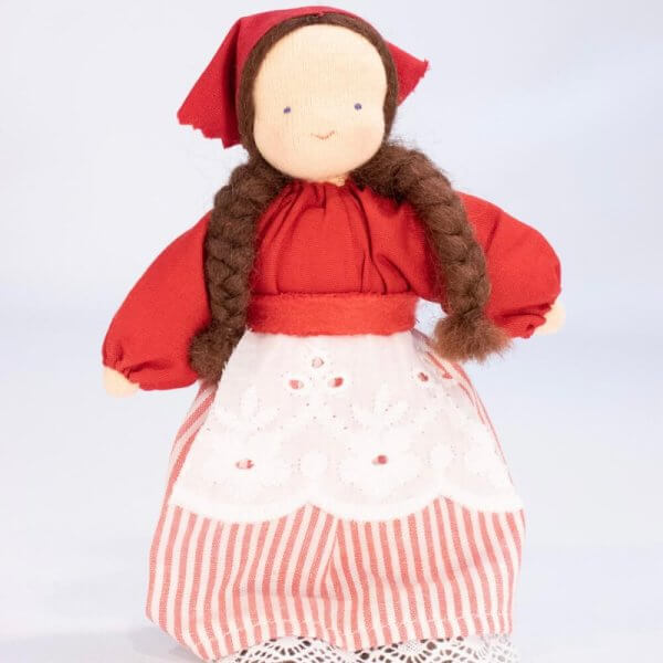 Summer girl Evi waldorf doll natural materials | Bambino Eco Toys Handmade cloth doll with brown braided hair, wearing a red dress and bonnet, white lace apron, and pink-striped pants.
