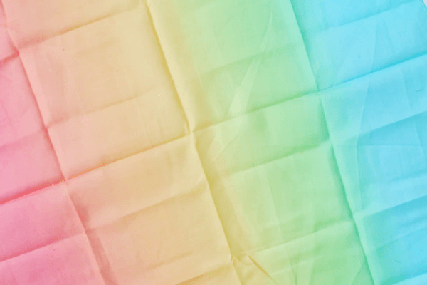 Lauras cotton play clothes rainbow and pastel rainbow | Bambino Eco Toys Close-up of fabric with a pastel rainbow gradient from pink to blue across diagonal panels.
